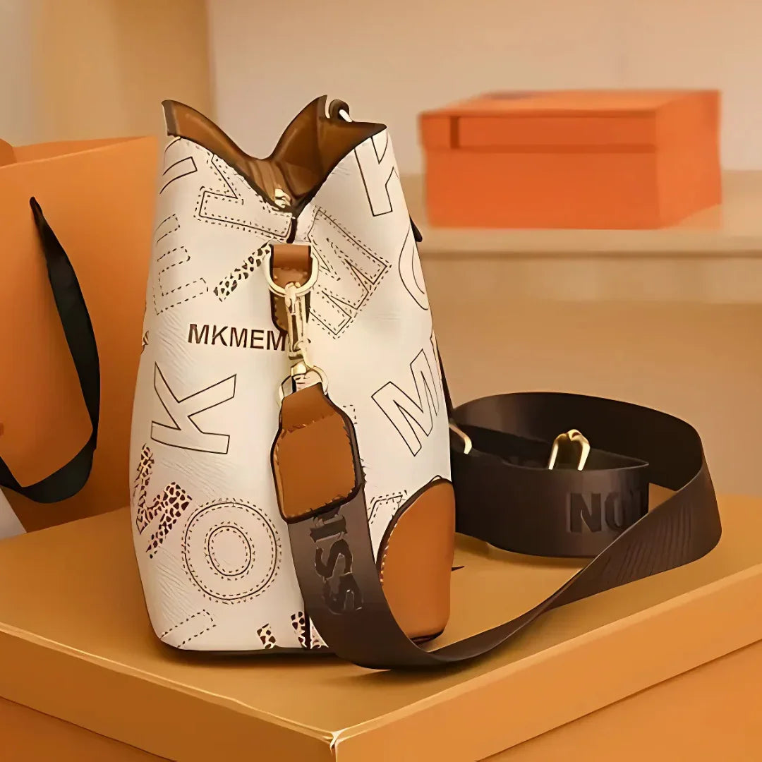 White and brown MKMEM bucket bag with bold letters and black strap on an orange box