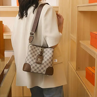 Woman in beige blazer carrying patterned designer shoulder bag in luxury store setting