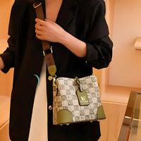 Woman in black blazer holding designer shoulder bag with green accents and printed pattern