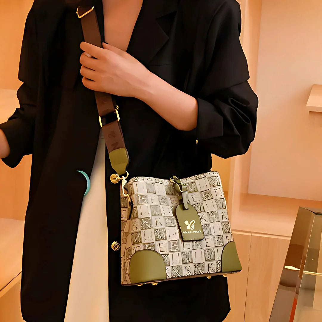 Woman in black blazer holding designer shoulder bag with green accents and printed pattern