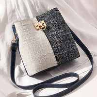 Textured crossbody bag with gold clasp, navy and cream colorblock on white fabric background