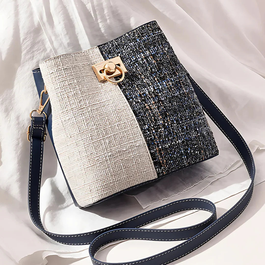 Textured crossbody bag with gold clasp, navy and cream colorblock on white fabric background