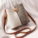 Two-tone tweed crossbody shoulder bag with gold clasp and brown strap on white fabric