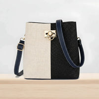 Two-tone bucket bag with gold hardware and navy strap on a wooden surface