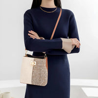 Woman in navy knit dress with gold chain necklace, carrying a colorblock crossbody handbag