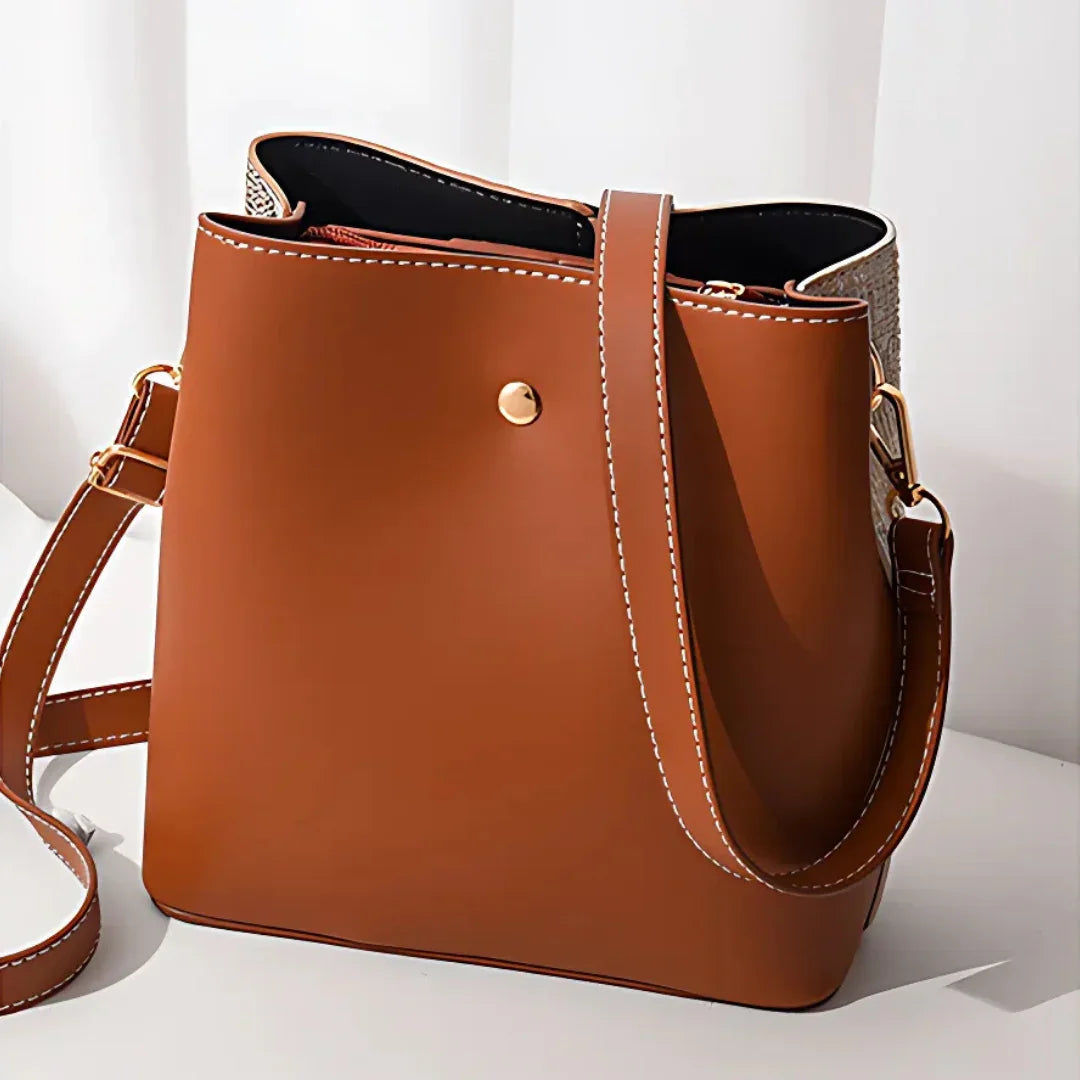 Brown leather shoulder bag with gold hardware on white background