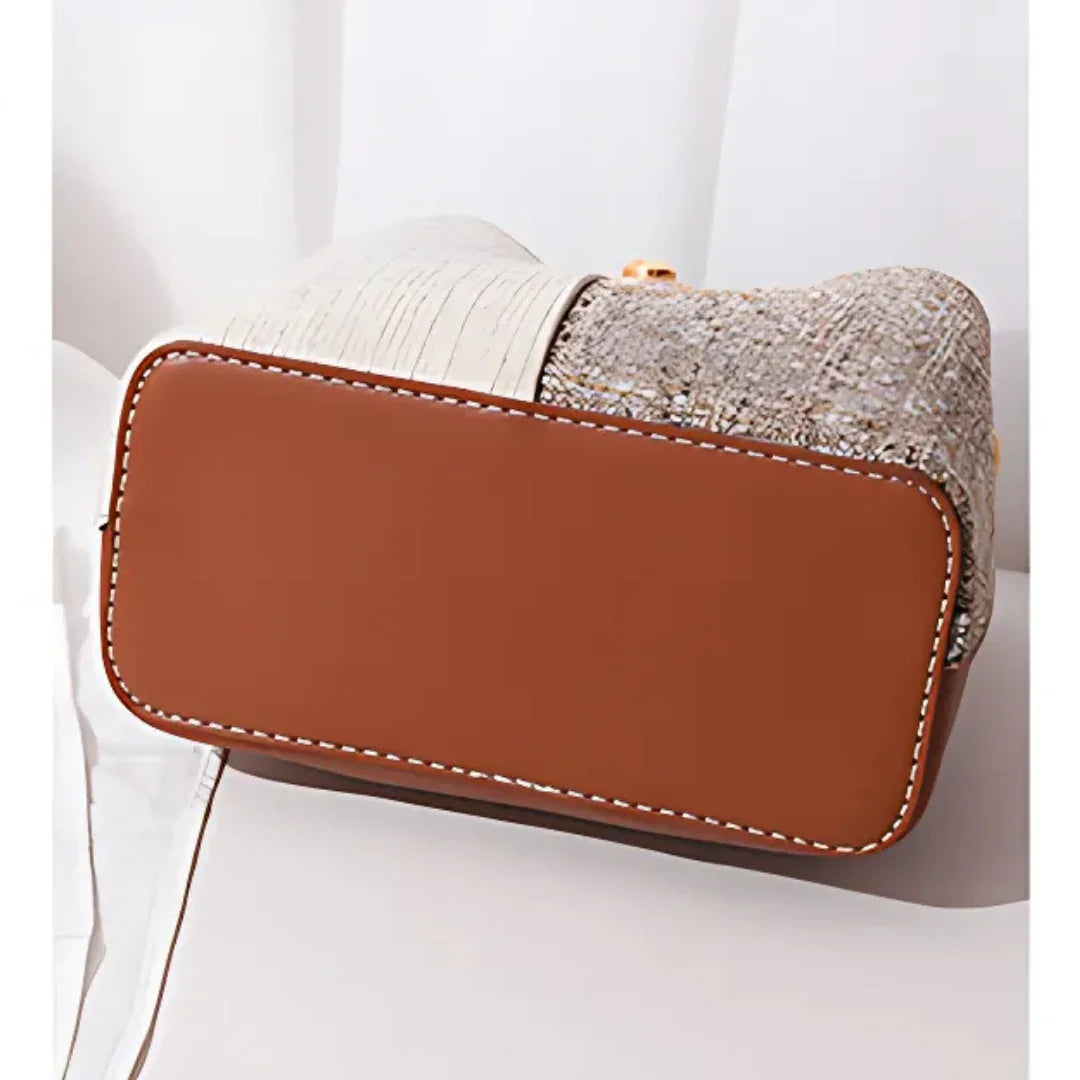 Brown leather bottom of a textured handbag on a white surface