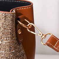 Close-up of brown leather and woven tote bag with gold metal clasp and stitching detail