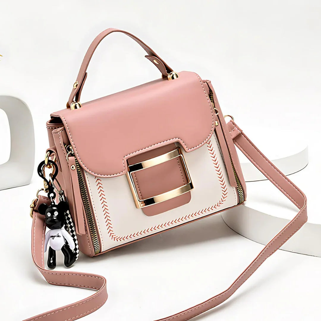 Pink and white handbag with gold buckle and bear keychain, crossbody strap