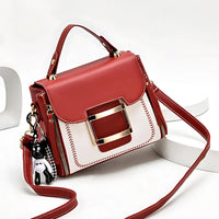 Red and white leather handbag with gold buckle, top handle, and bear keychain charm
