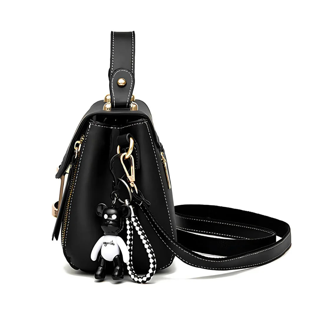 Black leather handbag with gold hardware and bear keychain accessory