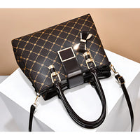 Black designer handbag with gold geometric pattern and glossy handles on white display