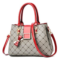 Gray patterned handbag with red patent leather handles, bow charm, and gold hardware