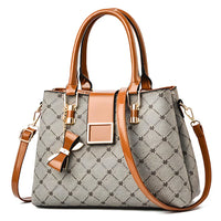 Elegant brown leather handbag with patterned gray fabric, bow detail, and gold hardware