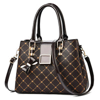 Elegant black and gold patterned handbag with top handles and bow charm