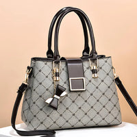 Elegant gray designer handbag with black handles, gold accents, and a bow charm
