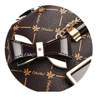 Brown designer handbag detail with gold bow charm and floral pattern