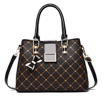 Black designer handbag with gold accents, diamond pattern, top handles, and bow keychain.