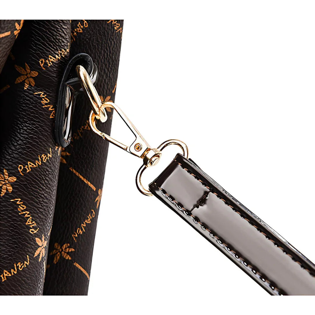 Close-up of black designer handbag strap with gold clasp and logo pattern