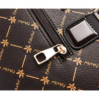 Close-up of brown leather handbag with gold zipper and floral print pattern