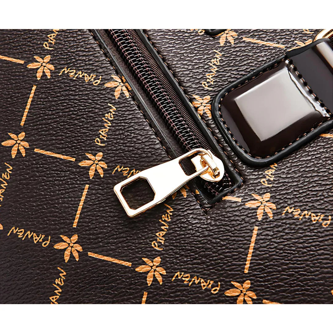 Close-up of brown leather handbag with gold zipper and floral print pattern