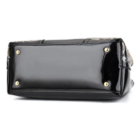 Black patent leather handbag bottom with gold metal feet, white background