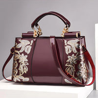Burgundy patent leather handbag with gold floral embroidery and detachable strap
