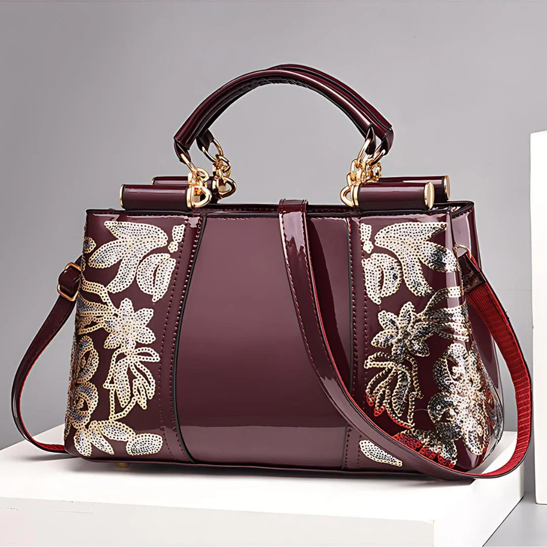 Burgundy patent leather handbag with gold floral embroidery and detachable strap