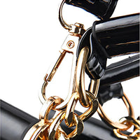 Close-up of gold chain and black patent leather handbag strap hardware