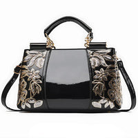 Black patent leather handbag with gold floral sequin embroidery and top handles