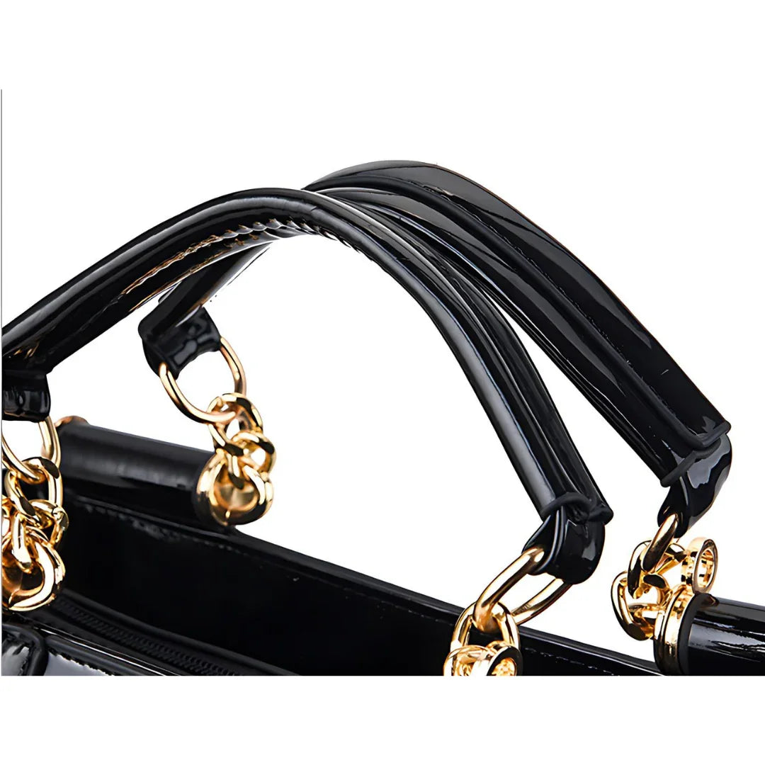 Black patent leather handbag with gold chain handles close-up
