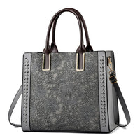 Gray floral embossed leather tote bag with dark brown handles and crossbody strap