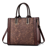 Brown leather tote bag with floral lace pattern and double handles