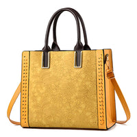 Yellow floral embossed tote bag with brown handles and detachable shoulder strap