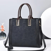 Elegant black leather tote bag with embossed floral pattern and braided side details