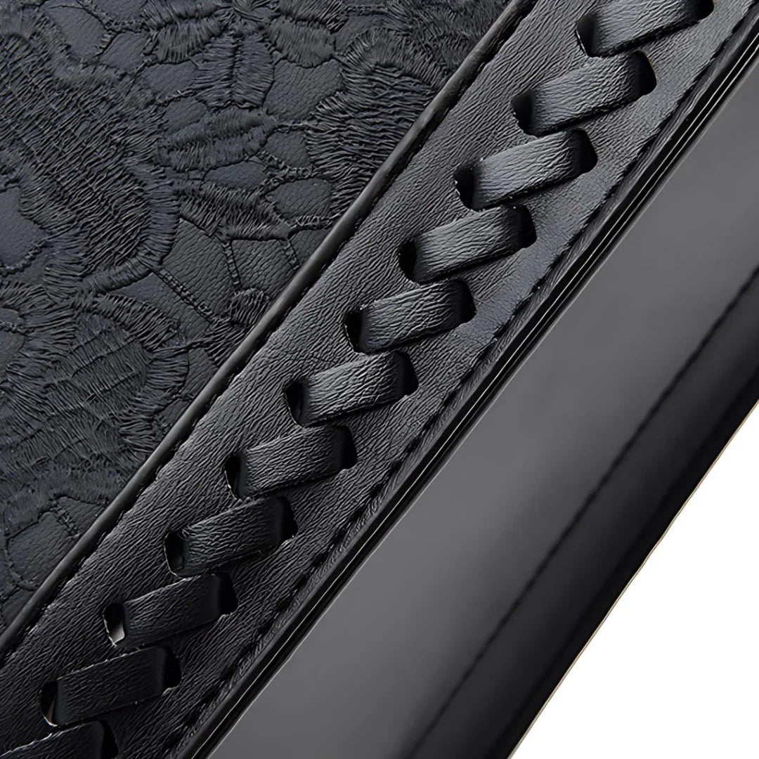 Black leather with embossed floral pattern and woven stitched detail, close-up