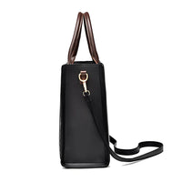 Side view of black leather handbag with brown handles and gold hardware