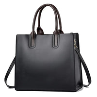 Black leather tote bag with dual brown handles and detachable shoulder strap