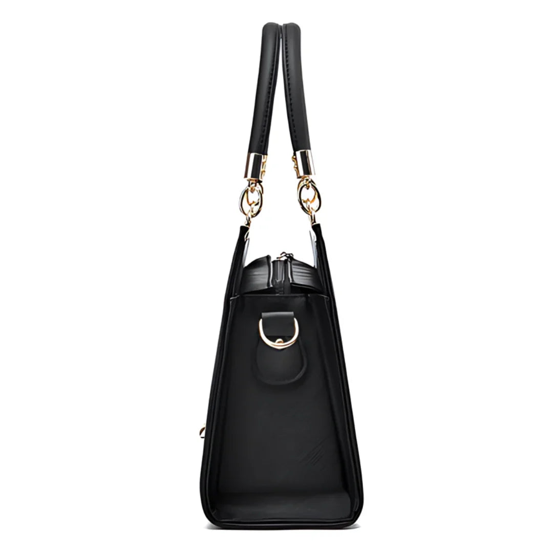 Side view of black leather handbag with gold hardware and double handles
