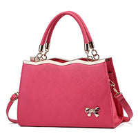 Elegant pink handbag with gold metal trim, top handles, and bow accent, women's fashion purse