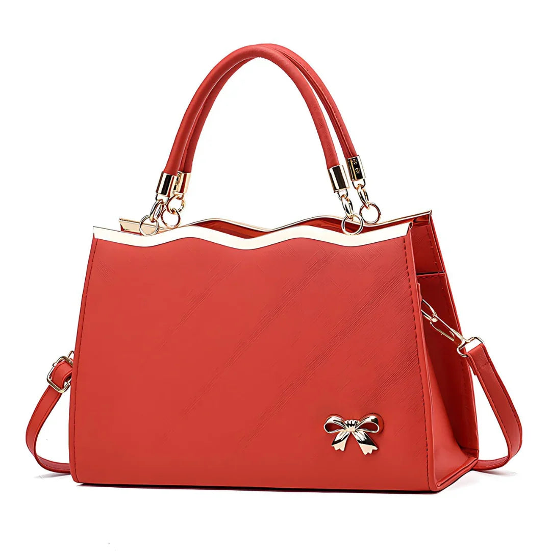 Elegant red women's handbag with gold accents and bow charm, top handle, and shoulder strap