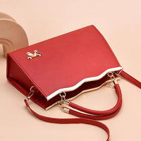 Red leather handbag with gold bow accent and wave edge on beige background