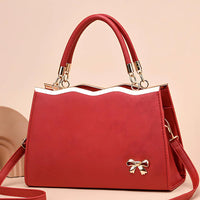 Red handbag with gold accents and bow detail, elegant purse on beige background