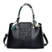 Black leather handbag with embossed floral pattern, printed scarf handles, and gold accents