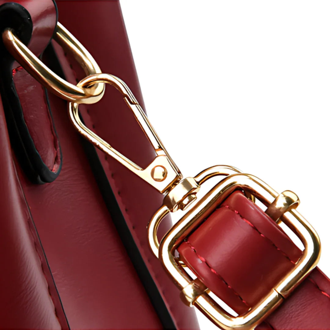 Close-up of red leather handbag with gold buckle and clasp detail