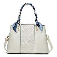 Elegant white handbag with embossed floral pattern, silk scarf handles, gold and pearl accents