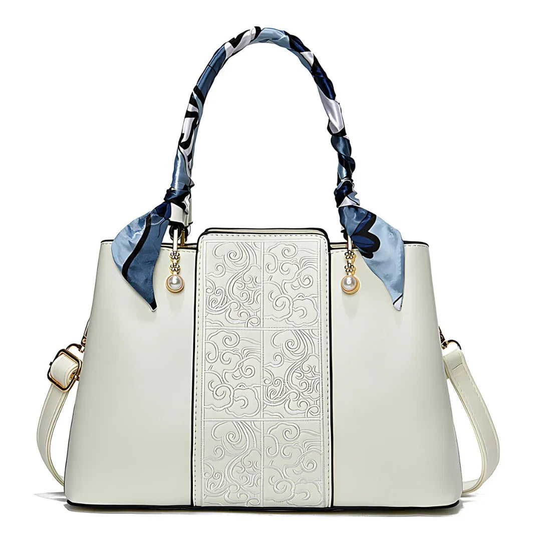 Elegant white handbag with embossed floral pattern, silk scarf handles, gold and pearl accents
