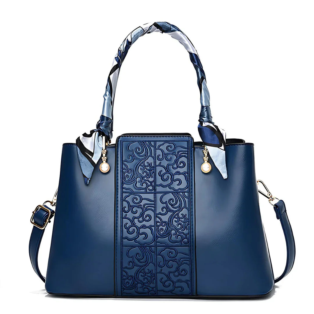 Elegant blue leather handbag with embossed pattern, scarf-wrapped handle, and gold accents