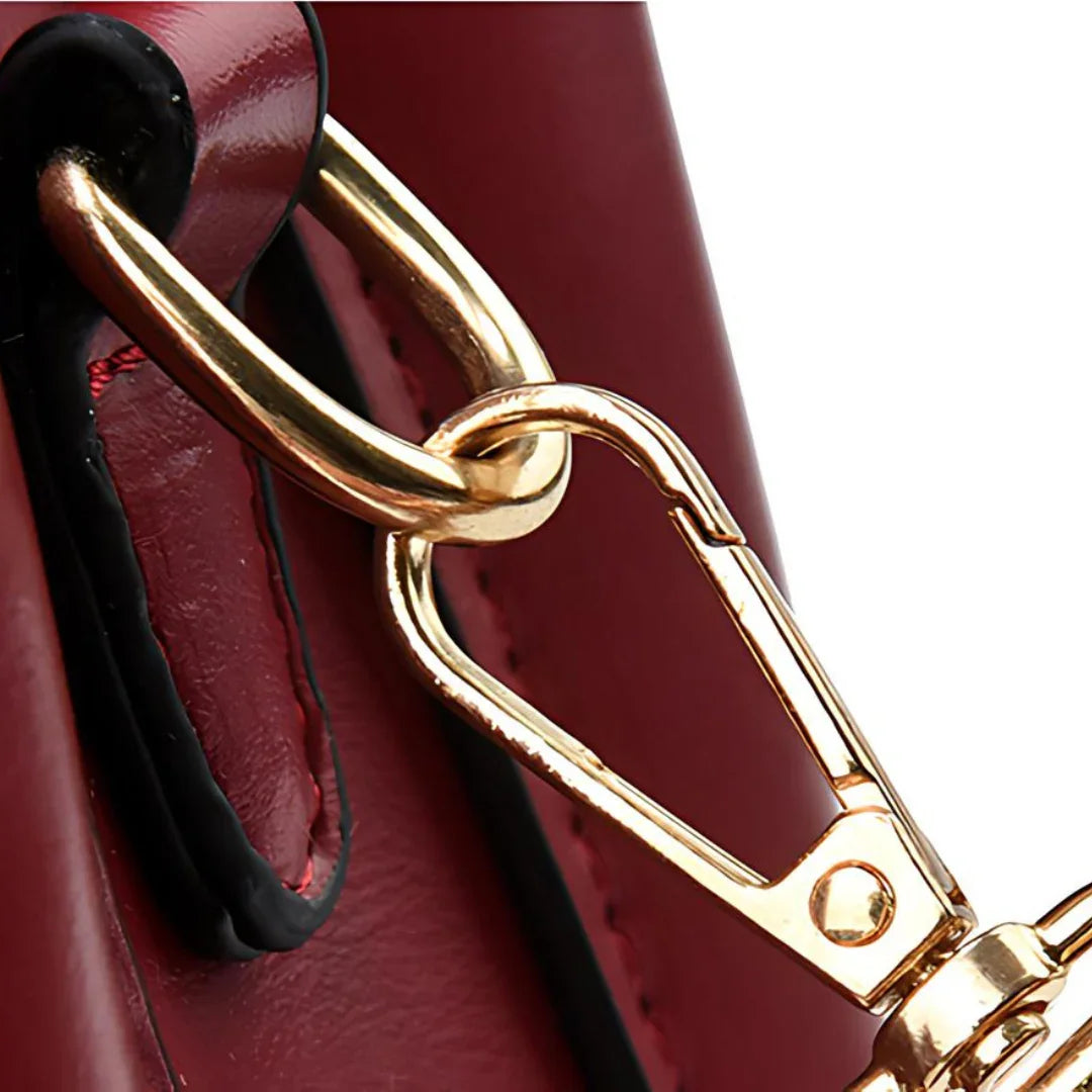 Gold metal clasp on burgundy leather handbag closeup