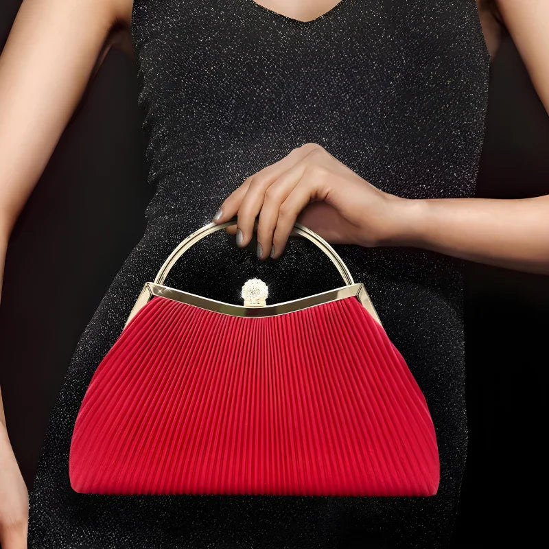 Woman in black dress holding elegant red pleated handbag with gold handle